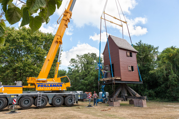 A crane lowers the windmill house into place on its post at Great Hopes Plantation.