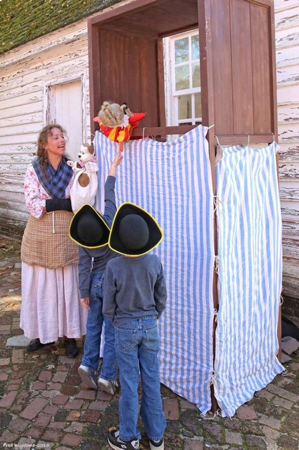 Two young visitors watch Donna Wolf as Sadie Gibbs during a puppet show. Photo by Fred Blystone.