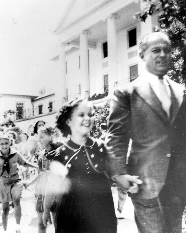 Child star Shirley Temple walks with her father George in front of the Williamsburg Inn in 1938.