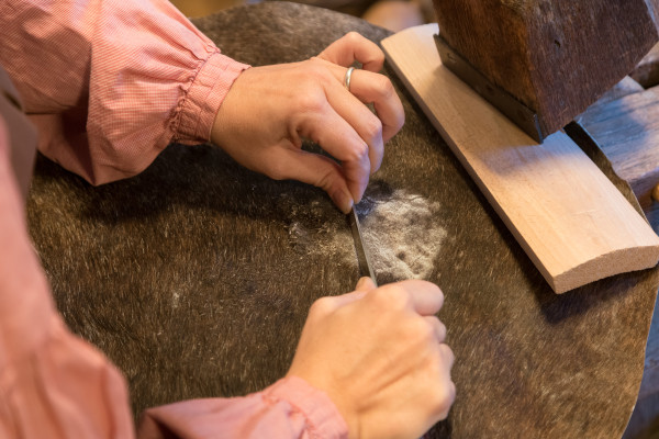 Ramona Vogel scrapes fur from cowhide that was used to make an African drum