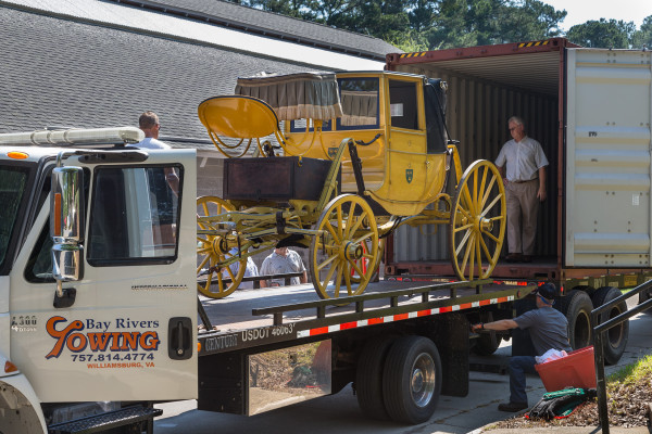 Richard Nicoll supervises loading carriages and the fire engine onto a shipping container for refurbishment in Poland by the Glinkowski Company. A flatbed tow truck is used to raise the carriages to the level of the container, then pushed in by hand. 