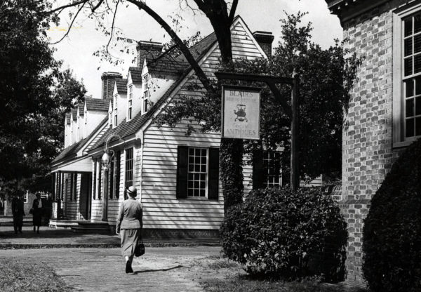 A woman walks past Blair's Antiques towards Chowning's Tavern, 1952