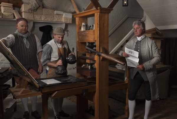 Dennis Watson (right) portrays Alexander Purdie, printer of the Virginia Gazette