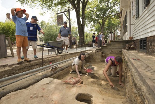 William & Mary Field School student Thomas Barto and Teaching Assistant Alexis Ohman excavate around an 18th-century porch pier in front of some interested site visitors.