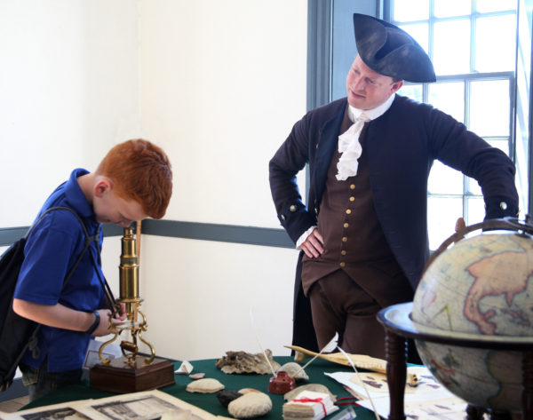 Young guest looks through a microscope at Wythe House as an interpreter looks on