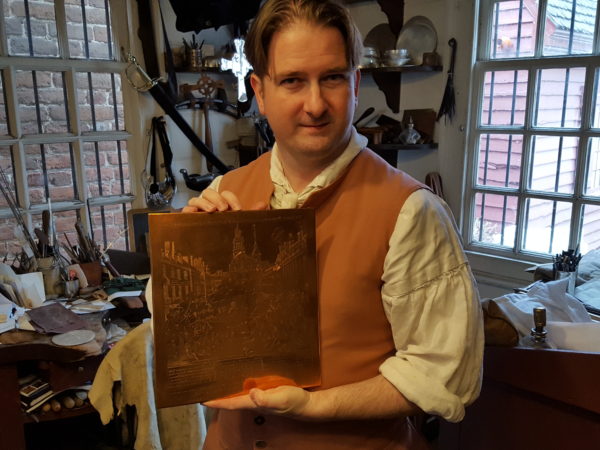 Apprentice silversmith Parker Brown holds the hand-copied engraving made by Lynn Zelesnikar, from which prints of Paul Revere's Boston Massacre print are made.